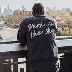 Man wearing Park in the Sky Crewneck in navy and looking out at the city from the High Line.