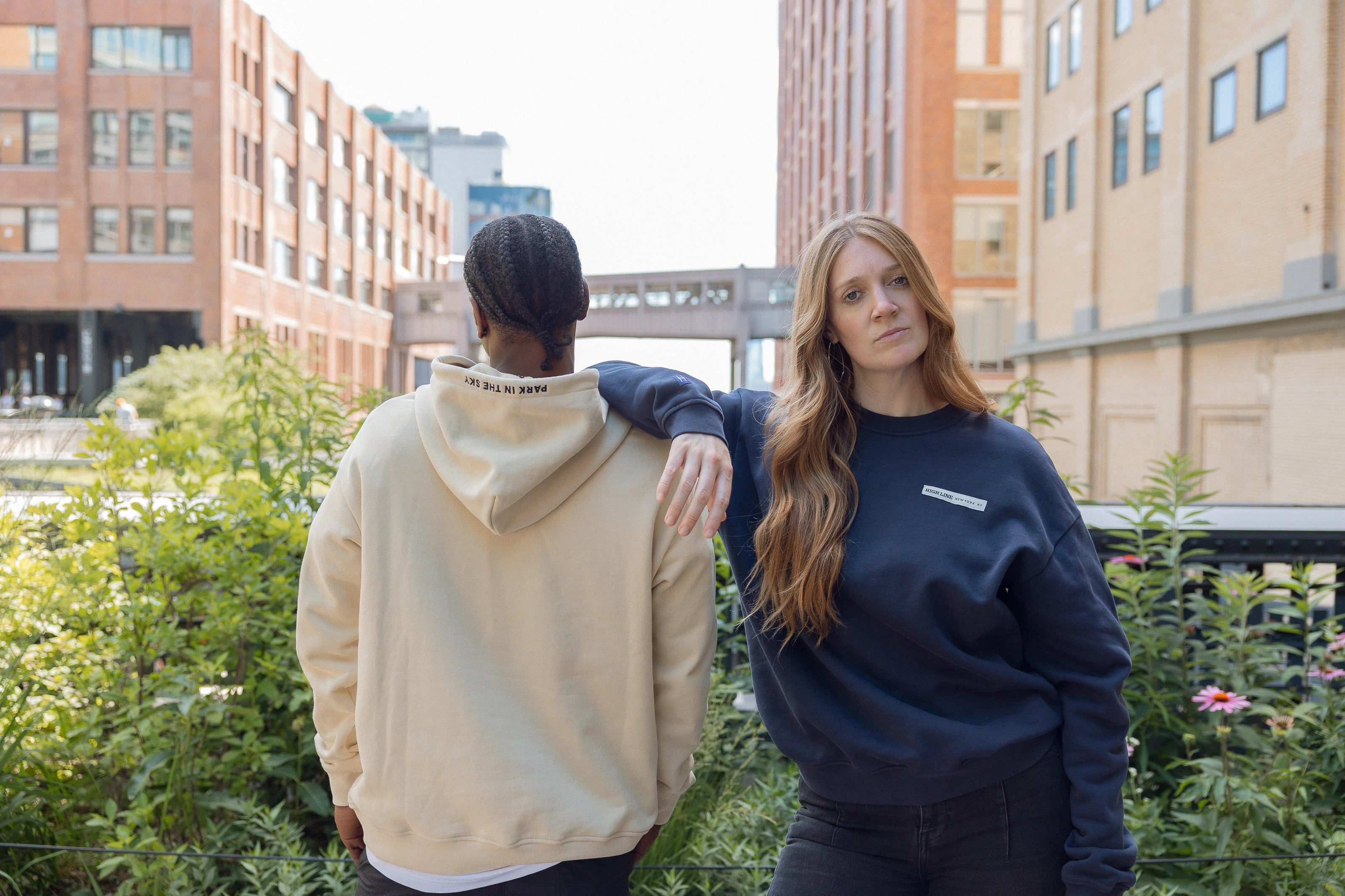 Woman wearing Park in the Sky crewneck and man in the Park in the Sky hoodie, with crewneck front and hood detail embroidery on the hoodie visible.