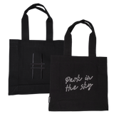 Both sides of the Park in the Sky Tote in Black—one side features the tagline "park in the sky" embroidered in white and the other the railroad track "H" icon embroidered in black against black canvas with black straps.