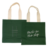 Both sides of the Park in the Sky Tote in Ivy—one side features the tagline "park in the sky" embroidered in white and the other the railroad track "H" icon embroidered in dark green against the dark Ivy green canvas with natural straps.