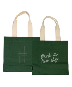 Both sides of the Park in the Sky Tote in Ivy—one side features the tagline "park in the sky" embroidered in white and the other the railroad track "H" icon embroidered in dark green against the dark Ivy green canvas with natural straps.