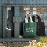 Park in the Sky Tote in Ivy and Park in the Sky Tote in Black hanging off of the railing of the High Line.