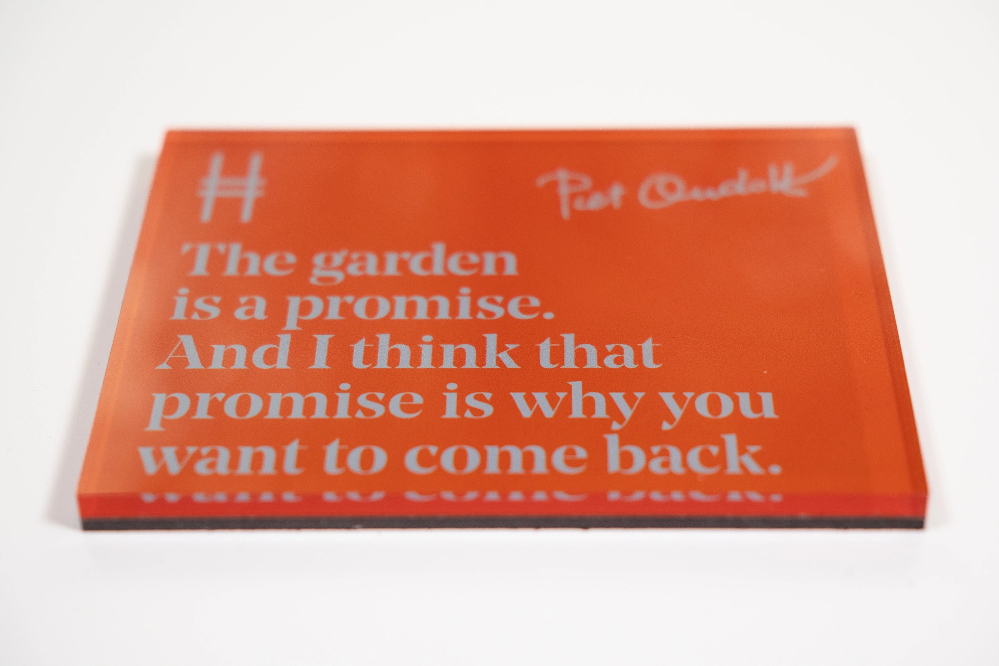 Acrylic fridge magnet featuring the quote "The garden is a promise. And I think that promise is why you want to come back." in pale blue against rich orange, with Piet Oudolf's signature and the High Line icon.