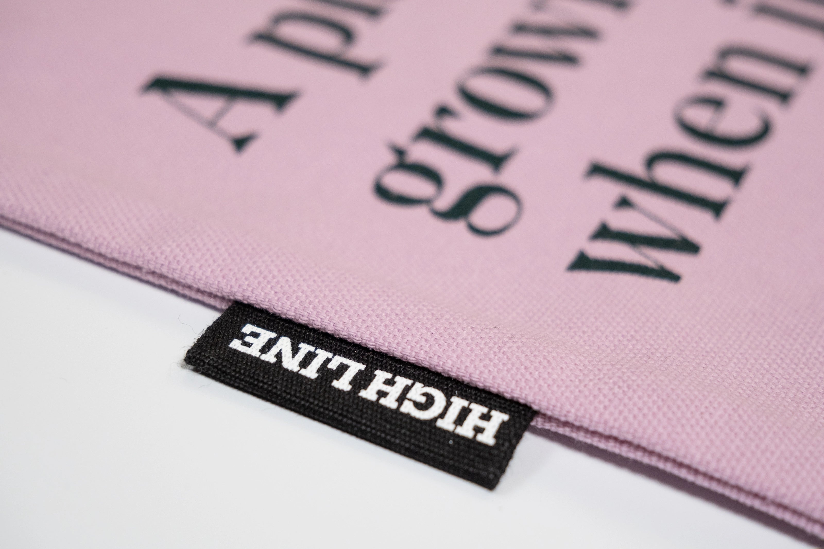 Closeup of the Piet Oudolf Quote Tote in Aster, showing the High Line tag and part of the quote.