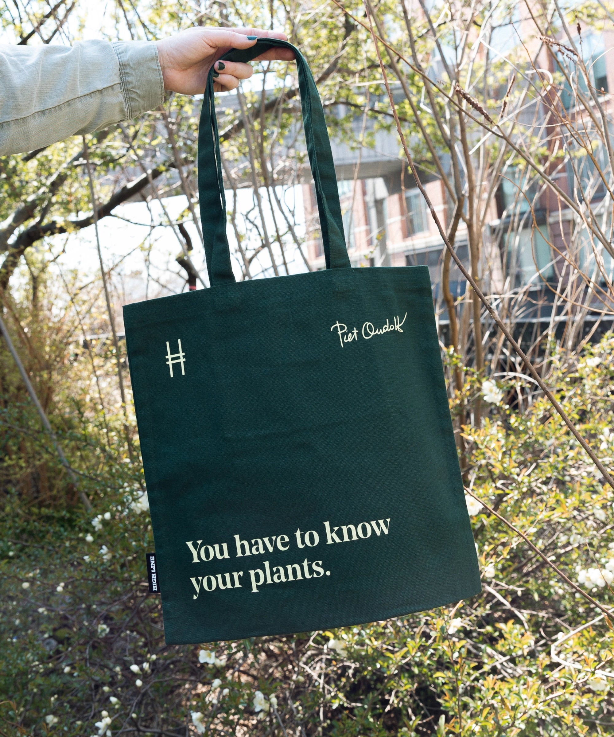Piet Oudolf quote tote in Ivy, featuring the quote "You have to know your plants" being held up against the foliage of the High Line.