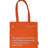 Piet Oudolf Quote Tote in Trumpet Honeysuckle—an orange cotton canvas tote bag featuring the quote "The garden is a promise. And I think that promise is why you want to come back." The quote, Oudolf's signature, and the High Line icon are all in a pale sky blue.