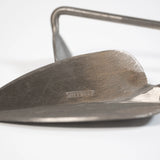 Closeup on the stainless steel trowel blade with hand hoe in the background. Sneeboer logo embossed on the trowel blade.