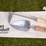 Sneeboer trowel and hand hoe with High Line icon and "Piet Oudolf collection" embossed on the wood handles shown on the carrying bag against moss.