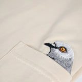Pigeon Pocket tee—detailed shot of chest pocket featuring a small embroidered pigeon head poking out of it. 