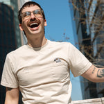 Person sitting on the High Line and laughing, wearing the Pigeon Pocket tee.