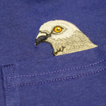 Closeup of Pigeon head embroidery popping out of the pocket on the Pigeon Pocket long-sleeve tee in Navy a rich, saturated, dark blue.