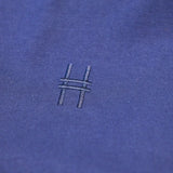 Closeup of the High Line icon, a railroad track inspired "H" embroidered on the Pigeon Pocket Longsleeve Tee in Navy.