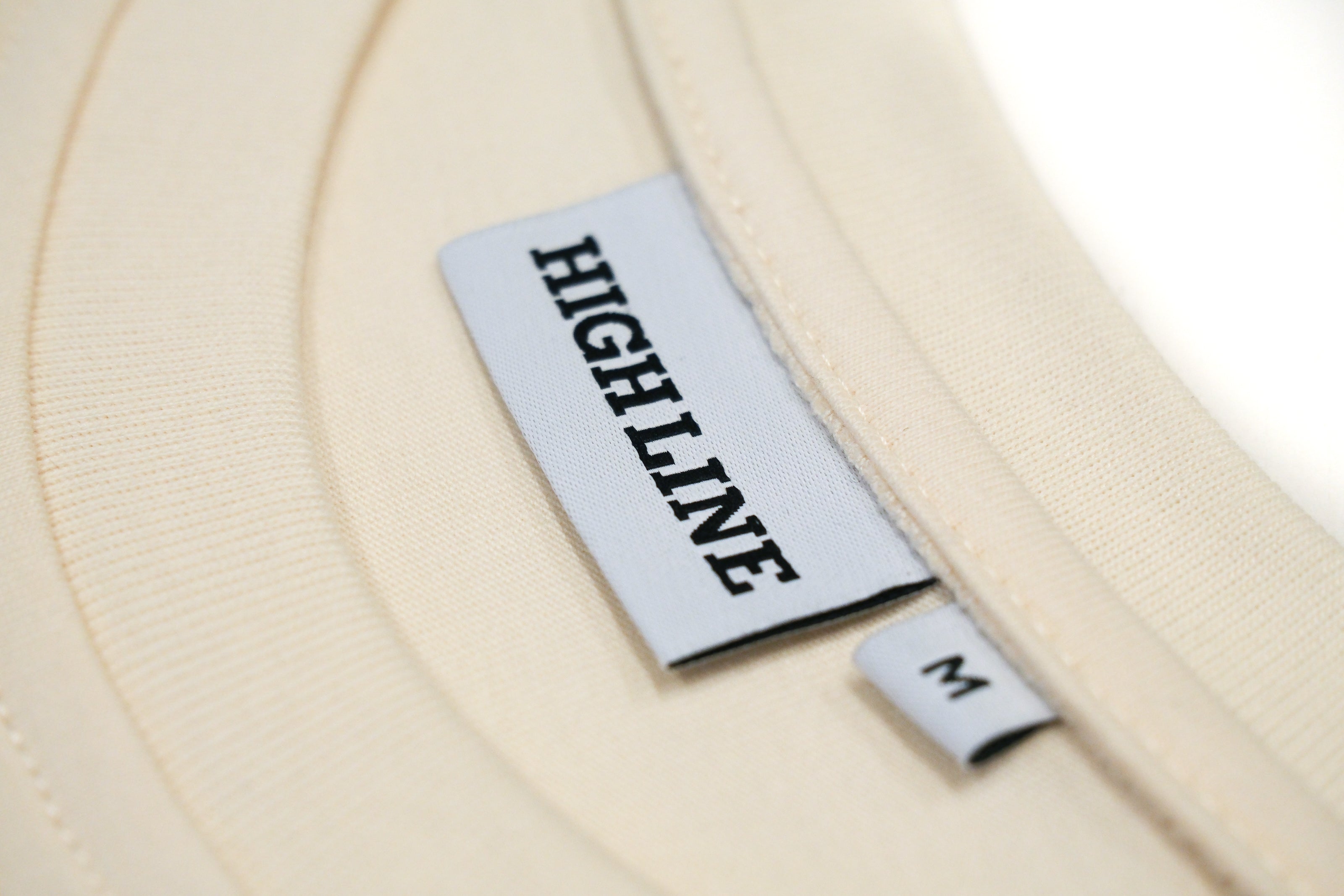 Closeup of the branded neck tag and size tag, as well as the ribbing at the neck of this long-sleeve crewneck t-shirt.