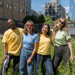 Four people in Protect Pollinators Tees standing amongst the foliage on the High Line, smiling and laughing.