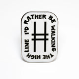 White enamel rectangular pin with rounded edges. At the center is the High Line icon, with the text "I'd rather be walking the High Line" wrapping around the border. Pin shown against a white background.