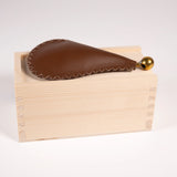 Leather and metal bird call for Sparrows sitting on top of its small wood box.