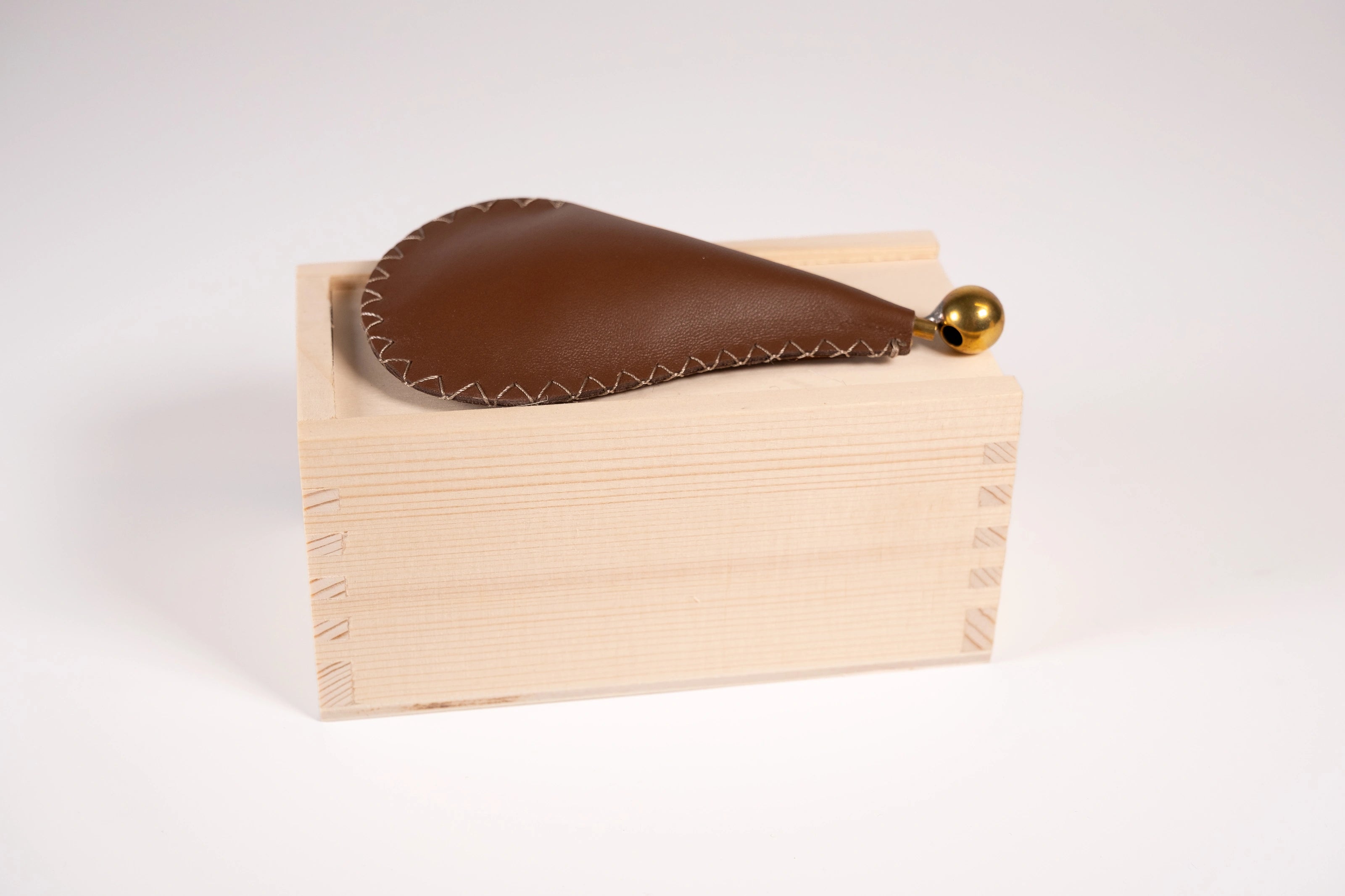 Leather and metal bird call for Sparrows sitting on top of its small wood box.