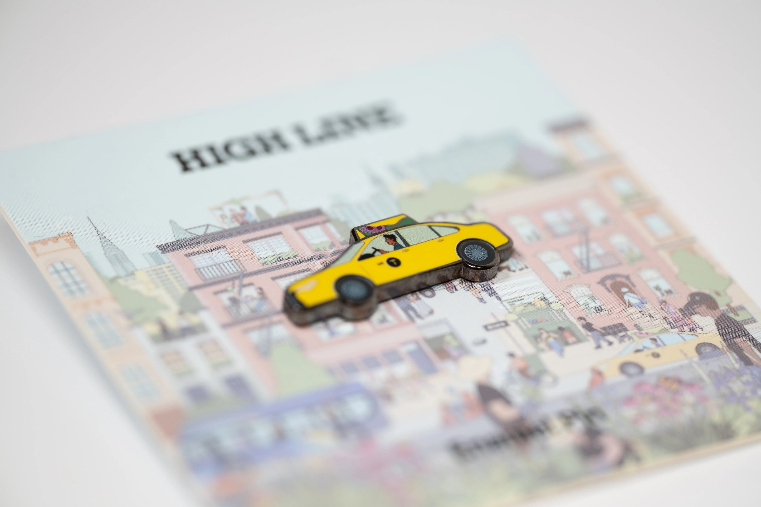Yellow taxi pin against the backing card featuring Jiaqi Wang's Nature in the City mural.