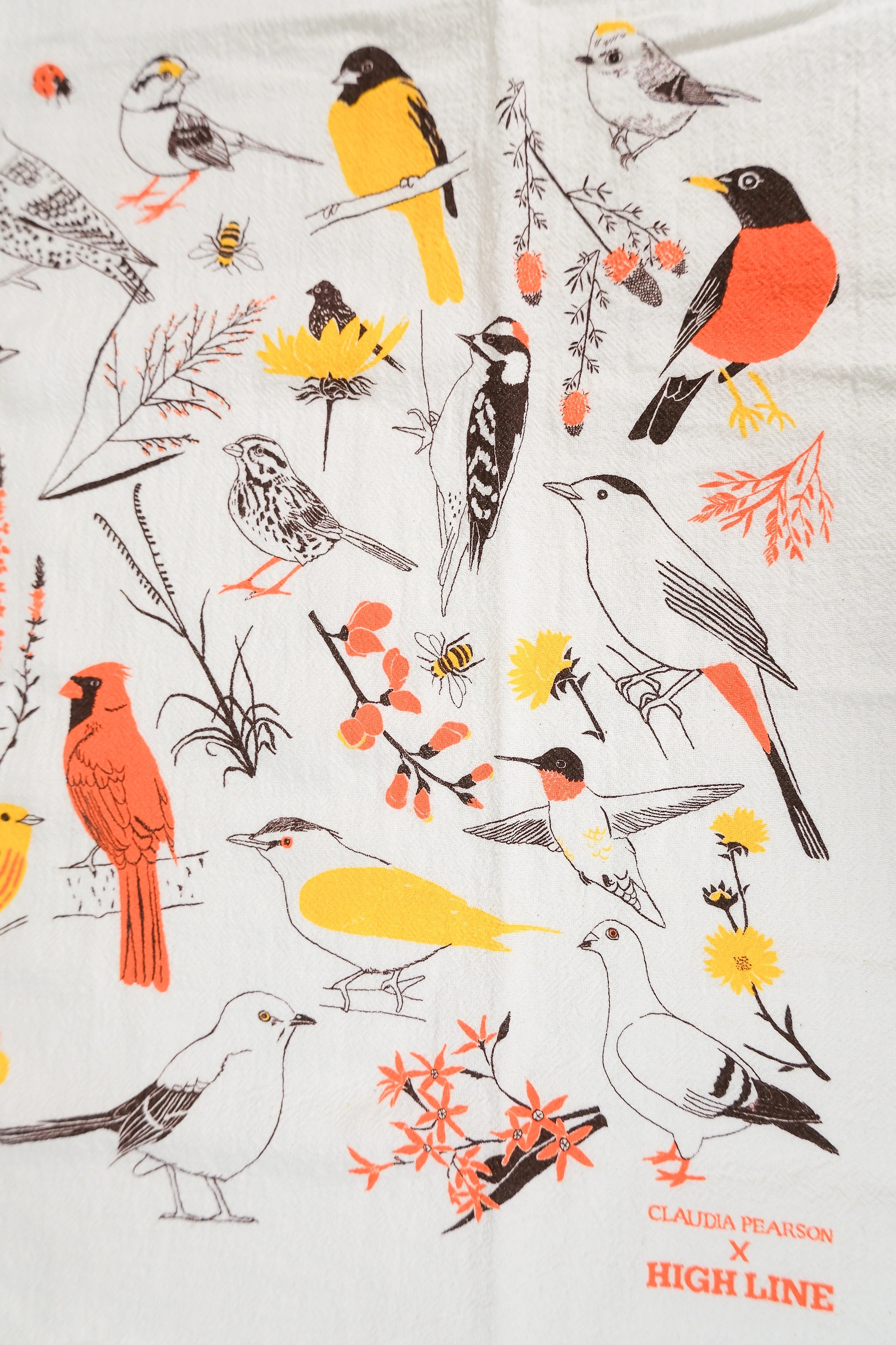 Claudia Pearson x High Line Washington Grassland tea towel in detail. The flour sack cotton tea towel is covered in illustrations of birds and plants that populate the High Line in browns, yellows and oranges.