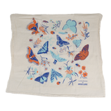 Claudia Pearson x High Line Wildflower Field tea towel, folded in half. The flour sack cotton tea towel is covered in illustrations of butterflies, ladybugs, moths, other insects and wildflowers in blues and oranges.
